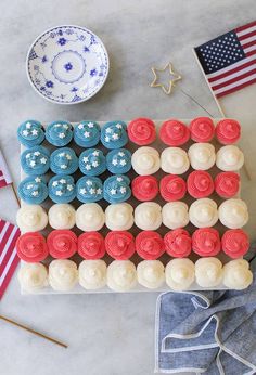 an american flag cake with red, white and blue cupcakes in the middle