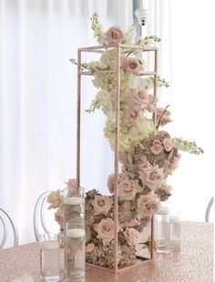 an arrangement of flowers and candles on a table