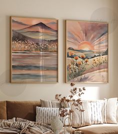 two paintings on the wall above a couch in a living room with pillows and blankets