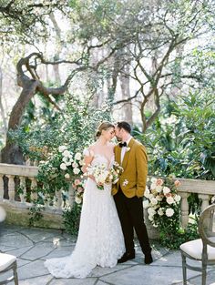 a bride and groom standing in front of an outdoor wedding ceremony area with greenery