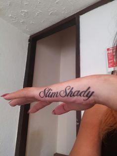 a woman is holding her arm with the word slim shady on it in cursive writing