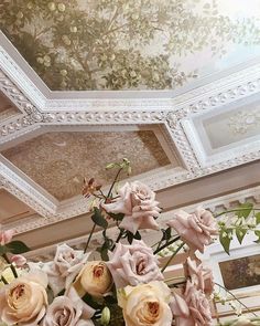 a vase filled with lots of pink flowers sitting on top of a table next to a mirror