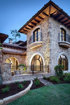 a large stone house with an iron fence around it's front porch and balconies on the second floor