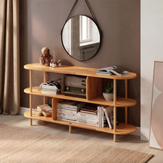 a round mirror hangs on the wall next to a shelf with books, magazines and other items