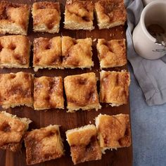 several pieces of cake sitting on top of a wooden cutting board next to a cup of coffee