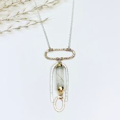 An archway of silver is textured by hand and surrounds a barrel of rutilated quartz, dropping from a gold oval pendant. Beams of gold pass through this unique gemstone accenting the tiny gold link dropping from it. •Sterling Silver and 14k Gold Filled •Rutilated Quartz •Pendant Dimensions: 1.75 x 3/4" •Length: 17" Gold Link, Jewelry Repair, Unique Gemstones, Oval Pendant, Rutilated Quartz, Quartz Pendant, Semi Precious Gemstones, Beams, Semi Precious