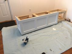 an unfinished bench being built on top of a sheet of blue tarp next to a pair of black high heel shoes