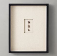 three stones are in a shadow box on the wall next to a framed piece of artwork