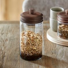 two jars filled with granola sitting on top of a wooden table