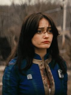 a woman with long black hair wearing a blue shirt