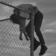 a man climbing up the side of a fence with his foot on top of a pole