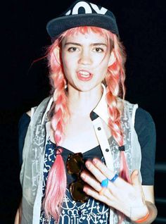 a young woman with pink hair wearing a hat and holding a cell phone in her hand