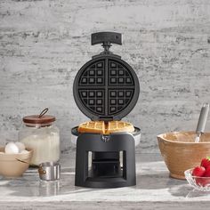 a waffle maker sitting on top of a counter next to eggs and other ingredients