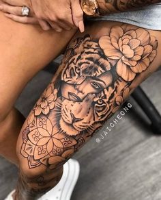 a woman's leg with a tiger and flowers tattoo on it