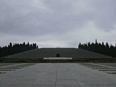 an empty concrete area with benches and trees in the background on a gloomy day