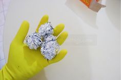 a person wearing yellow gloves holds three pieces of foil in their hand, on top of a white surface