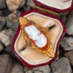 This vintage north-to-south cameo ring features a bezel set hard stone cameo with an elongated floral bezel. The ring is crafted in 14k yellow gold and has been re-shanked with 10k yellow gold. The ring also features a high carat gold wash with natural patina. Vintage Cameo Signet Ring, Art Nouveau Oval Cameo Jewelry, Vintage Cameo Signet Ring For Anniversary, Heirloom Oval Cameo Signet Ring, Vintage Cameo Ring With Oval Cabochon, Vintage Cameo Oval Cabochon Rings, Antique Oval Cameo Signet Ring, Antique Cameo Signet Ring Collectible, Antique Cameo Signet Ring For Weddings