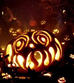 pumpkins carved into the shape of faces and swirls are lit up at night