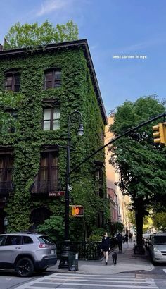 an apartment building covered in vines on the corner of a street with traffic lights and people walking by