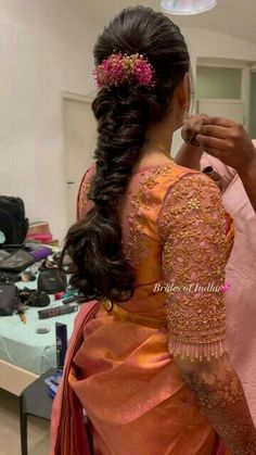 a woman is getting her hair done by another woman in an orange sari and pink blouse