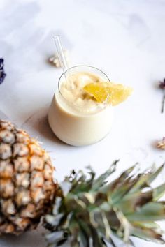 a pineapple next to a smoothie on a table