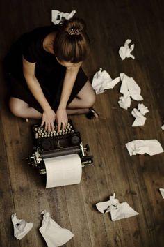 a woman is sitting on the floor with toilet paper all over her and she is typing on an old typewriter