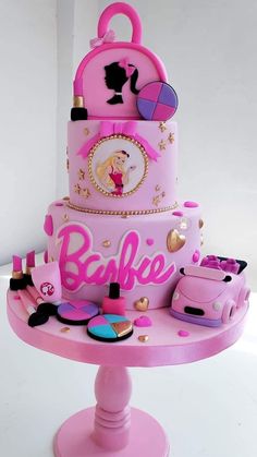 there is a pink cake with barbie's on it and other items around the cake