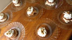 small desserts are arranged on glass plates on a wooden table, ready to be eaten