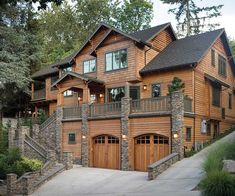 a large wooden house with two garages on the front and second story, surrounded by trees