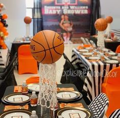 an orange and black sports themed baby shower is set up with basketballs on the table