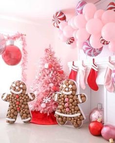 a pink christmas tree decorated with gingerbread man and woman cookies in front of a fireplace