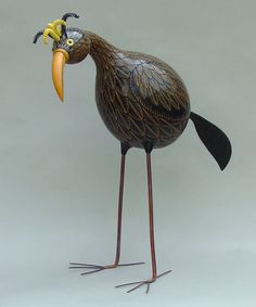 a statue of a bird with a large beak and long legs, standing on one leg