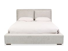 an upholstered bed with white sheets and pillows