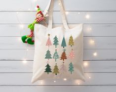 a white bag with christmas trees on it next to a green elf's hat