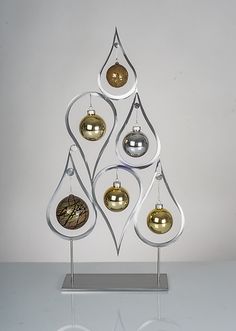 a christmas tree made out of ornaments on top of a metal stand with three balls hanging from it