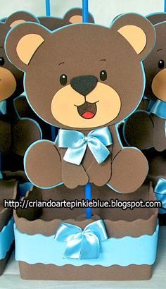 there are many brown teddy bears sitting in blue boxes with bows on the top and bottom