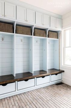 an empty room with several white shelves and baskets on the top, along with wood flooring