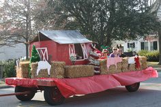 a red truck with hay bales on the back and people in costumes riding down the street