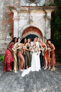 a group of women standing next to each other in front of a stone wall and doorway