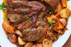 a white plate topped with meat, potatoes and carrots next to a wooden table