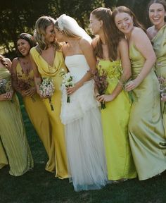 a group of women standing next to each other in long dresses and holding bouquets