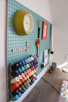 there is a clock on the wall and many different items are hanging on the pegboard