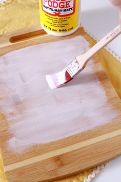 a paintbrush is being used on a wooden tray