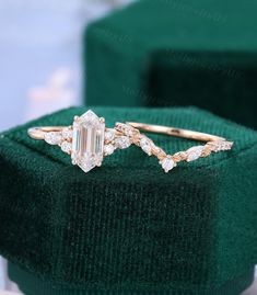 an emerald colored diamond ring sitting on top of a green velvet box