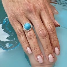 a woman's hand with a ring on her finger next to a swimming pool