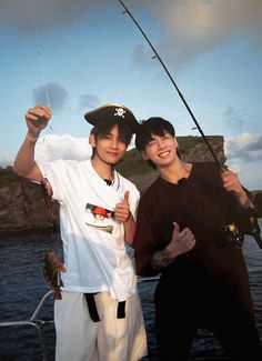 two young men standing next to each other on a boat