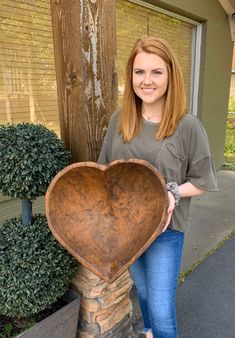 a woman standing next to a wooden heart