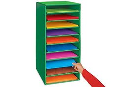 a child's hand is reaching into a green shelf with colorful folders on it