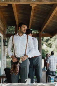 two men standing next to each other wearing suspenders