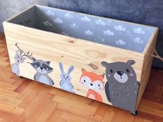 a wooden box with animals painted on the front and sides, sitting on a wood floor